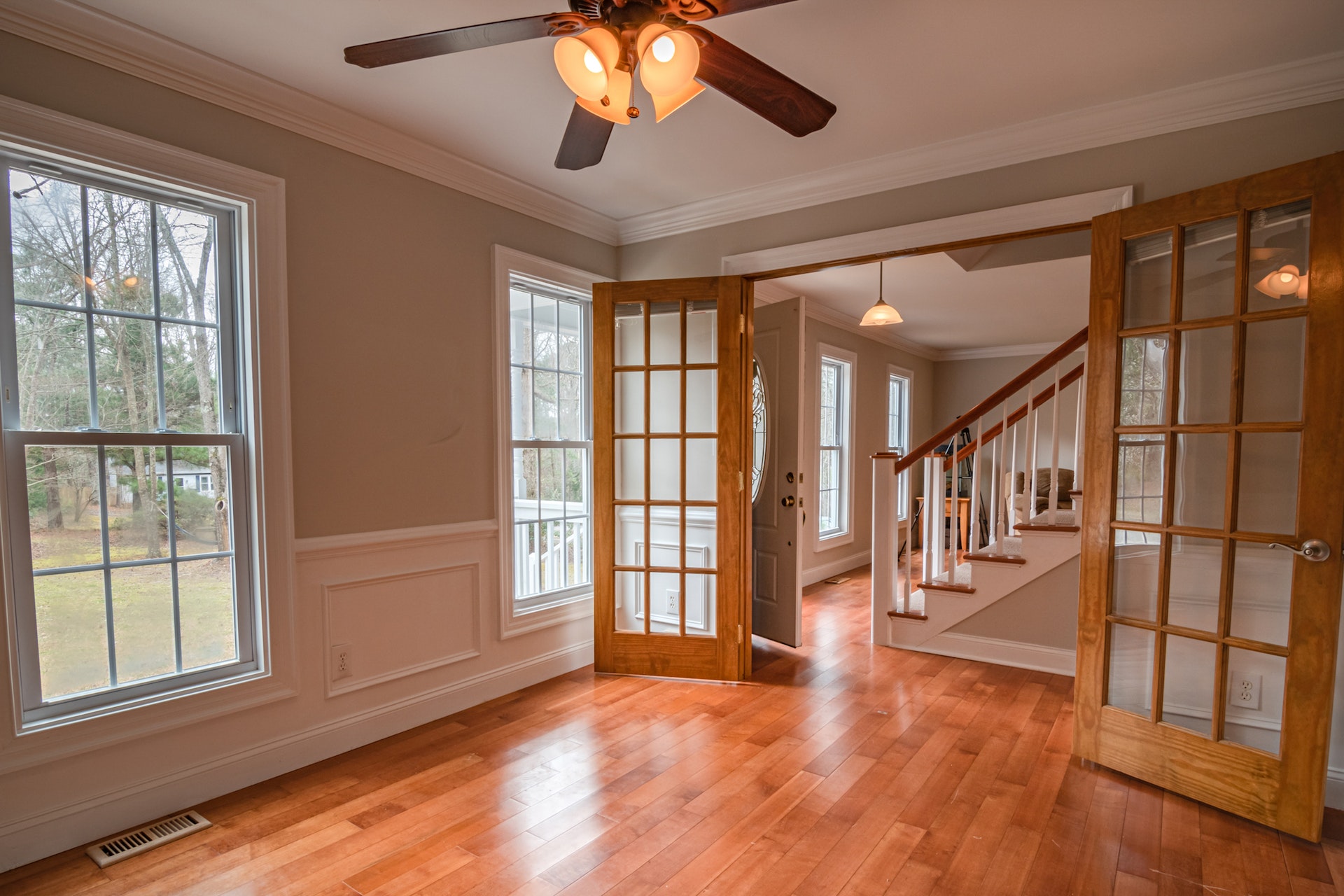 Spacious home entryway with hardwood floors, beige walls, wooden doors, and natural light