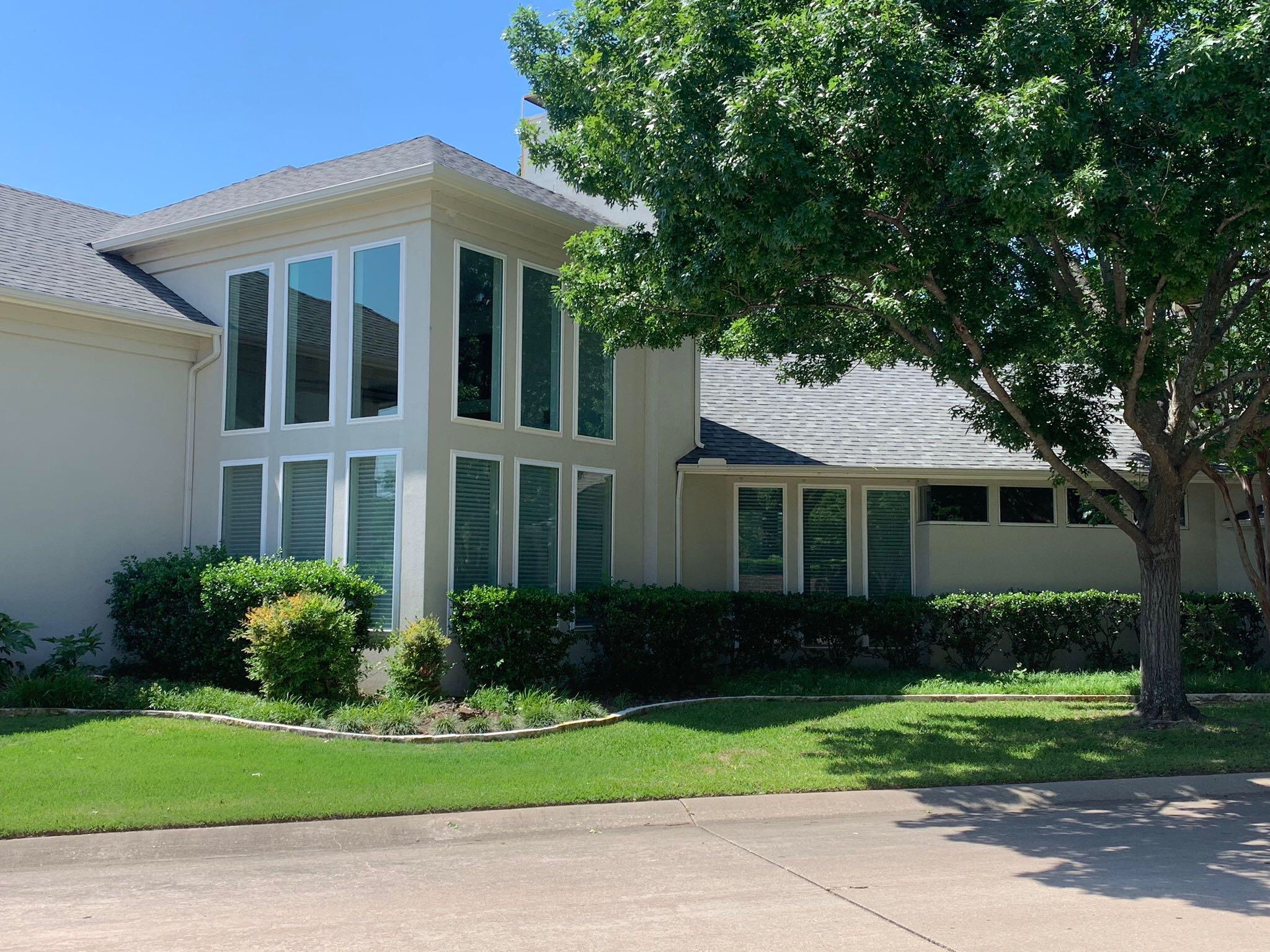 Modern white residential home with green shutters and manicured lawn in suburban setting
