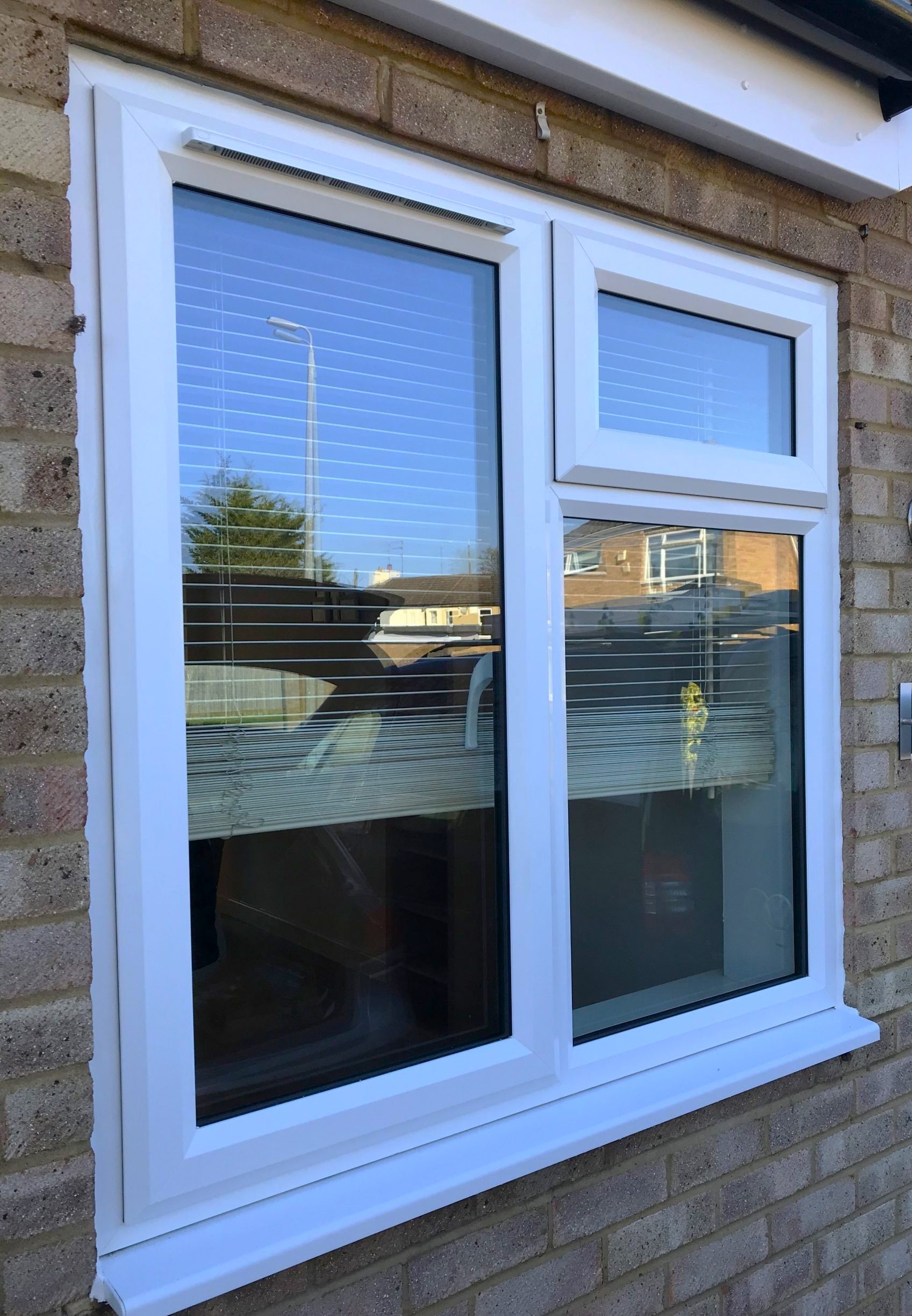 Modern white uPVC double-glazed window with integrated blinds installed on brick exterior wall