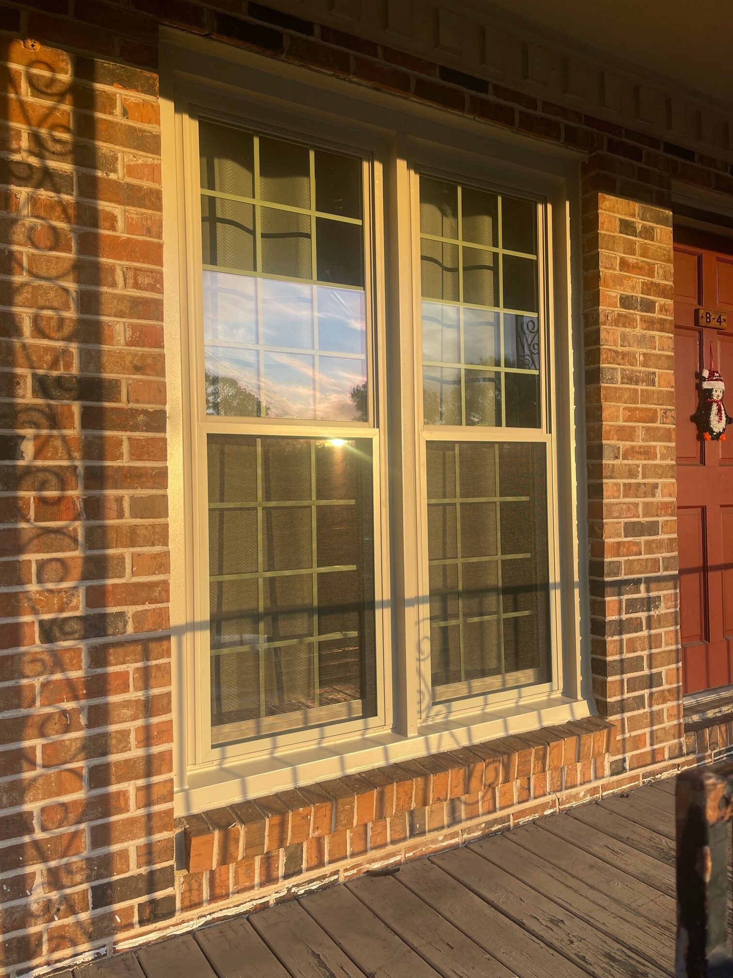 Cream-colored double-hung window on brick house exterior with golden afternoon sunlight
